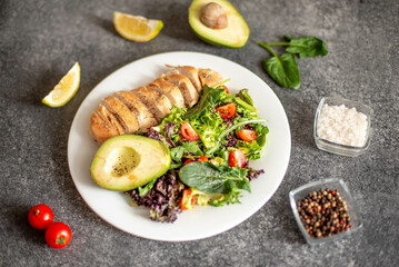 Grilled chicken meat and fresh vegetable salad of tomato, avocado, lettuce and spinach. Healthy and detox food concept. Ketogenic diet.