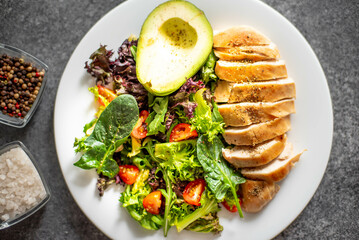 Grilled chicken meat and fresh vegetable salad of tomato, avocado, lettuce and spinach. Healthy and detox food concept. Ketogenic diet.