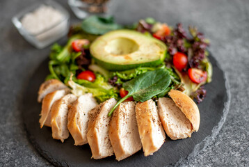 Grilled chicken meat and fresh vegetable salad of tomato, avocado, lettuce and spinach. Healthy and detox food concept. Ketogenic diet.