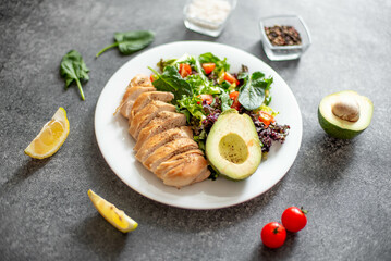 Grilled chicken meat and fresh vegetable salad of tomato, avocado, lettuce and spinach. Healthy and detox food concept. Ketogenic diet.