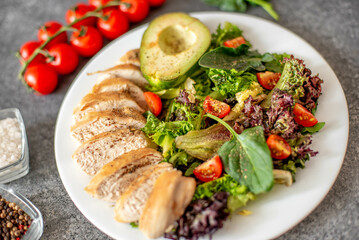 Grilled chicken meat and fresh vegetable salad of tomato, avocado, lettuce and spinach. Healthy and detox food concept. Ketogenic diet.