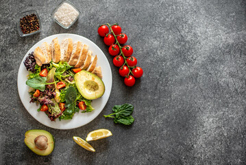 Grilled chicken meat and fresh vegetable salad of tomato, avocado, lettuce and spinach. Healthy and detox food concept with copy space for your text . Ketogenic diet.