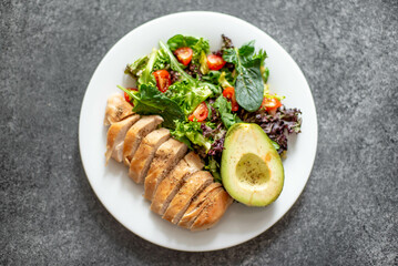 Grilled chicken meat and fresh vegetable salad of tomato, avocado, lettuce and spinach. Healthy and detox food concept. Ketogenic diet.