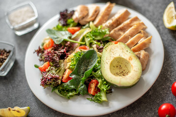 Grilled chicken meat and fresh vegetable salad of tomato, avocado, lettuce and spinach. Healthy and detox food concept. Ketogenic diet.