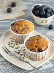 Muffins with blueberry and lavender in rustic style. Cupcakes on the ceramic plate with a pattern of blueberries. Mini cakes on the grey wooden table.