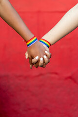 lesbian couple holding hands with gay pride bracelet