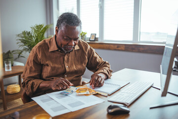 Serious African American man  in living room manage budget received invoice analyzes month expenses...