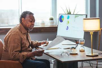 Shot of a senior man looking stressed while going through paperwork at home. Man analyzes month expenses feels concerned about public utility debt