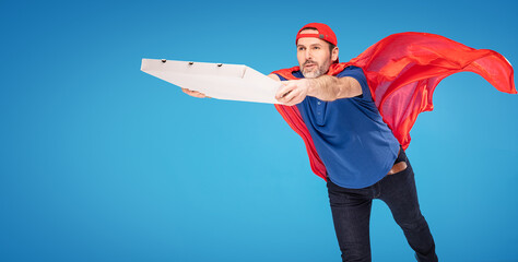Super hero pizza delivery guy flying on blue studio background