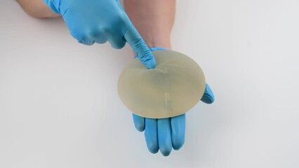 A plastic surgeon shows a breast silicone implant.