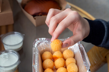 The girl eats cheese balls in foil packaging. Takeaway food, fast food, unhealthy food.