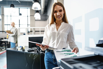 Young employee using modern printer in office