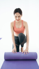 Asian Sport fit young woman yoga instructor wear sportswear rolling unrolling yoga pilates rubber...