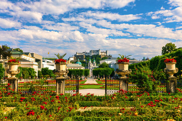 Beautiful view of famous Mirabell Gardens with the old historic Fortress Hohensalzburg in the background in Salzburg, Austria. Famous Mirabell Gardens with historic Fortress in Salzburg, Austria. - obrazy, fototapety, plakaty