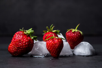 Strawberries with ice on a black background. cold refreshing fruit