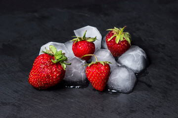Strawberries with ice on a black background. cold refreshing fruit