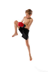 Little boy, kid in sports shots and gloves practicing thai boxing on white studio background. Sport, education, action, motion concept.