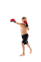 Punching. Little boy, kid in sports shots and gloves practicing thai boxing on white studio...