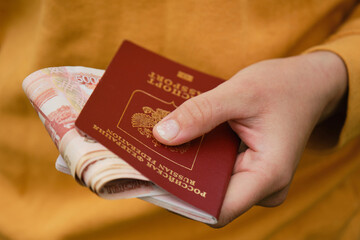 Concept of travel or immigration. Relocation with Russian passport and cash with face value of five thousand rubles. Woman holds red passport of Russian with hands and cash money.