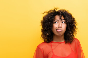 thoughtful african american woman grimacing and looking away isolated on yellow.