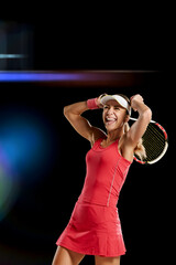 Beautiful happy woman enjoing tennis game on black studio background