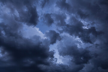 Fototapeta na wymiar Epic Dramatic storm dark grey cumulus rain clouds against blue sky background texture, thunderstorm 