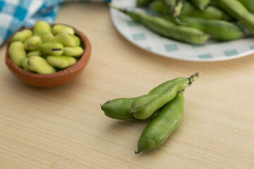 Broad beans in shell on a kitchen table, with copy space