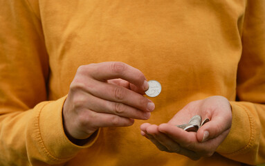 Concept of poor human. Russian coins hold in hands and count. Crisis and economic downturn. Russian woman considers savings cash. Only mans hands and money, yellow clothes.