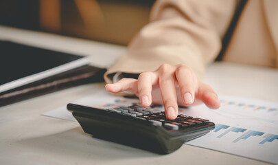 business woman or accountant who are using a calculator to calculate business data Accounting documents and laptop computer at the office business idea
