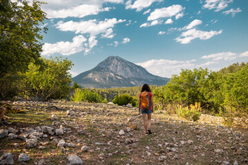 A woman with a backpack against the backdrop of a beautiful mountain and sky