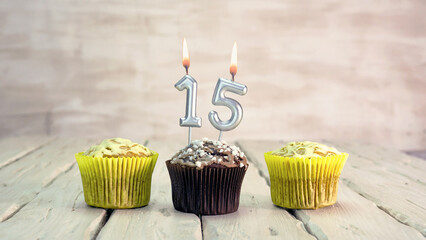Happy birthday muffins with candles with the number 15. Card copy space with pies for...