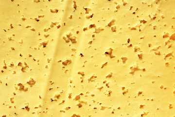 the surface of a cut piece of cheese with holes background backdrop