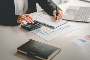 business woman or accountant who are using a calculator to calculate business data Accounting documents and laptop computer at the office business idea