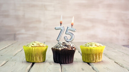 Happy birthday muffins with candles with the number 75. Card copy space with pies for...