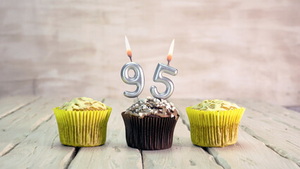 Happy birthday muffins with candles with the number 95. Card copy space with pies for...