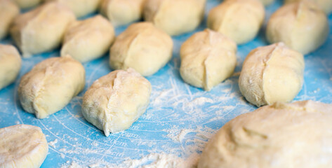 Stuffed pies lie on the table. The process of cooking pies with potatoes and meat at home. Close-up. Selective focus.