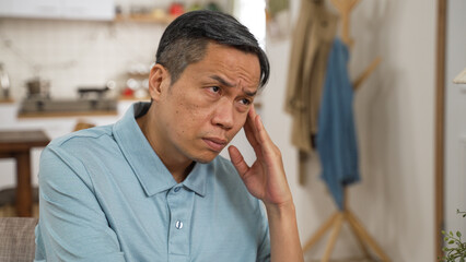 closeup of stressed asian elderly male worrying about problem alone at home. he props his head...
