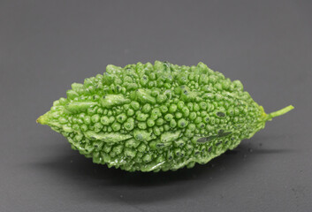 single Bitter melon or Bitter gourd with drop of water isolated on black background