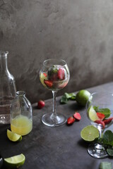 Preparation of lemonade from strawberries, lemon and fresh mint. Pieces of fruit and mint in a transparent glass