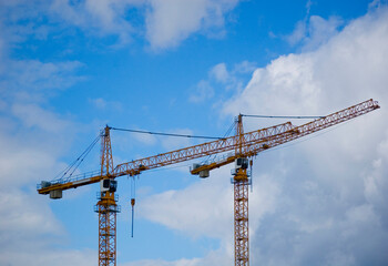 Large construction site crane working on a building complex with cloudy sky.