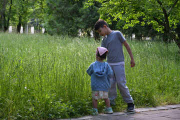Naklejka na ściany i meble Boy and girl playing in the park on a summer evening
