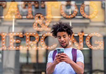 young afro man looking at his smartphone surprised