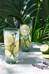 Cool lavender lemonade with lime slices and lavender flower on the table near dark green wall and...