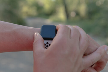 Runner man connecting his digital watch with the satellite to start the route. Close-up image of a young athlete starting his modern white stopwatch before starting the continuous race along the river