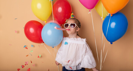 Happy Birthday party. Child girl with balloons on beige background