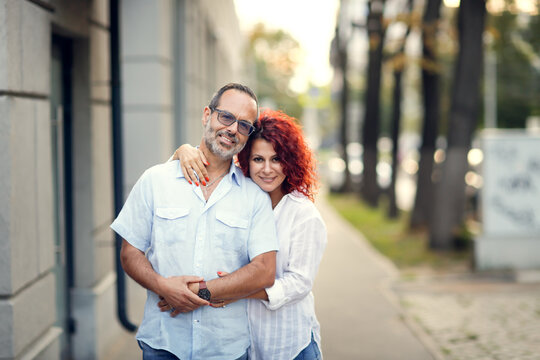 Fototapeta Cute middle aged european couple hugging on walk in city street in summer