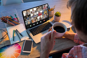 Businessman having black coffee while video conferencing colleagues through laptop in office