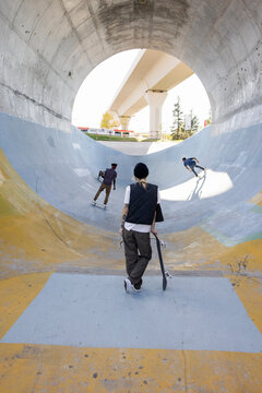 Skater watching friends in tunnel in skatepark