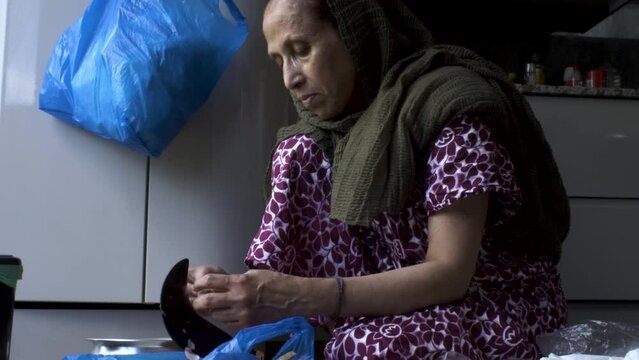 A Muslim old woman cutting the meat into small pieces on Eid al-Adha at home.
