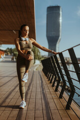 Young woman in sportswear exercising on a river promenade